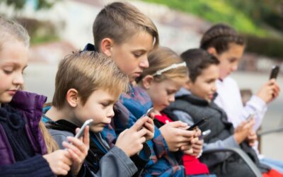 Dzieci na dworze wpatrzone w ekrany smartfonów